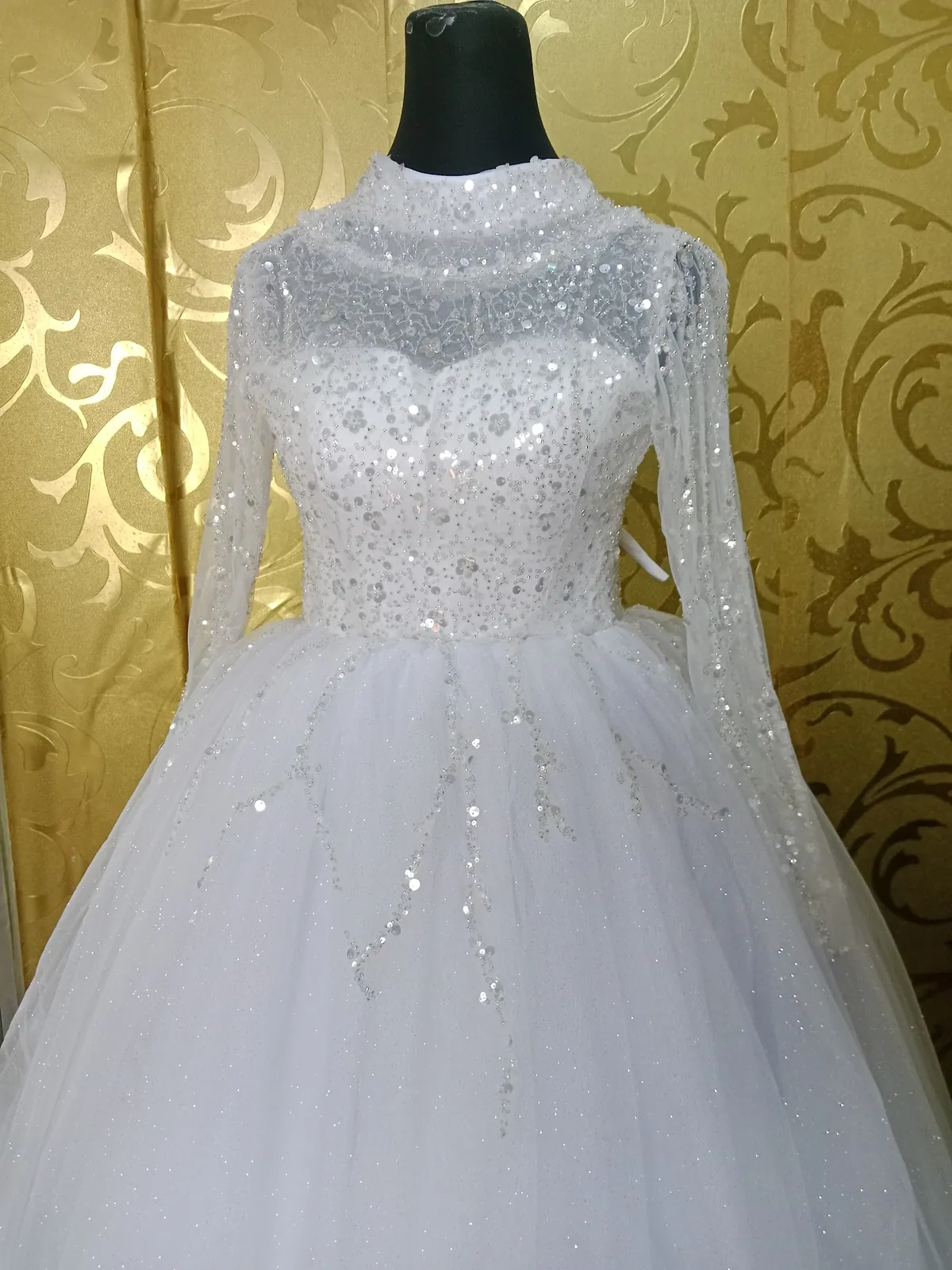 Long-sleeved embellished bridal gown on a mannequin